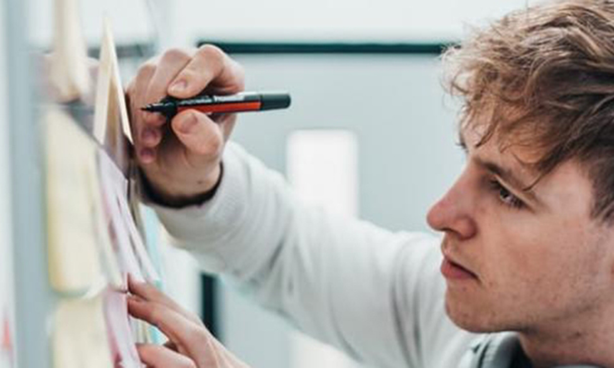 Man working at white board making notes on serious of sticky notes.